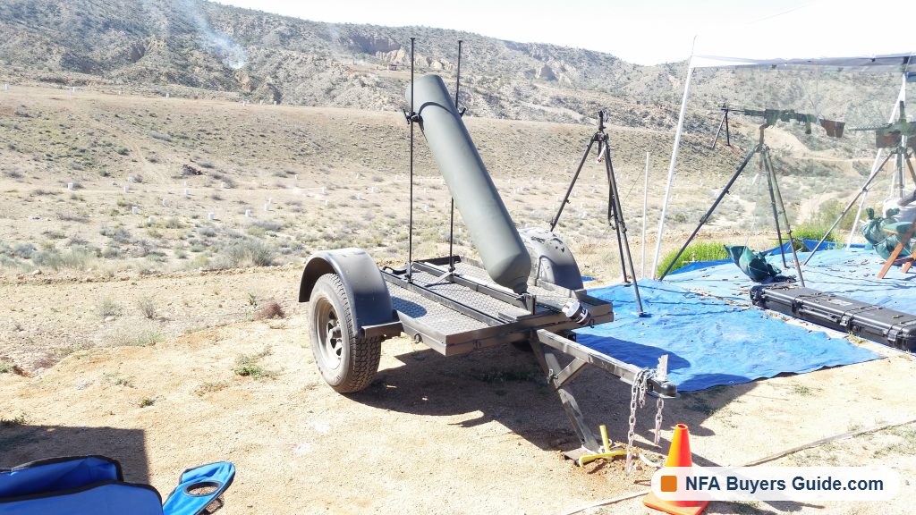 Trailer-mounted mortar tube on the range with tripod guns behind it